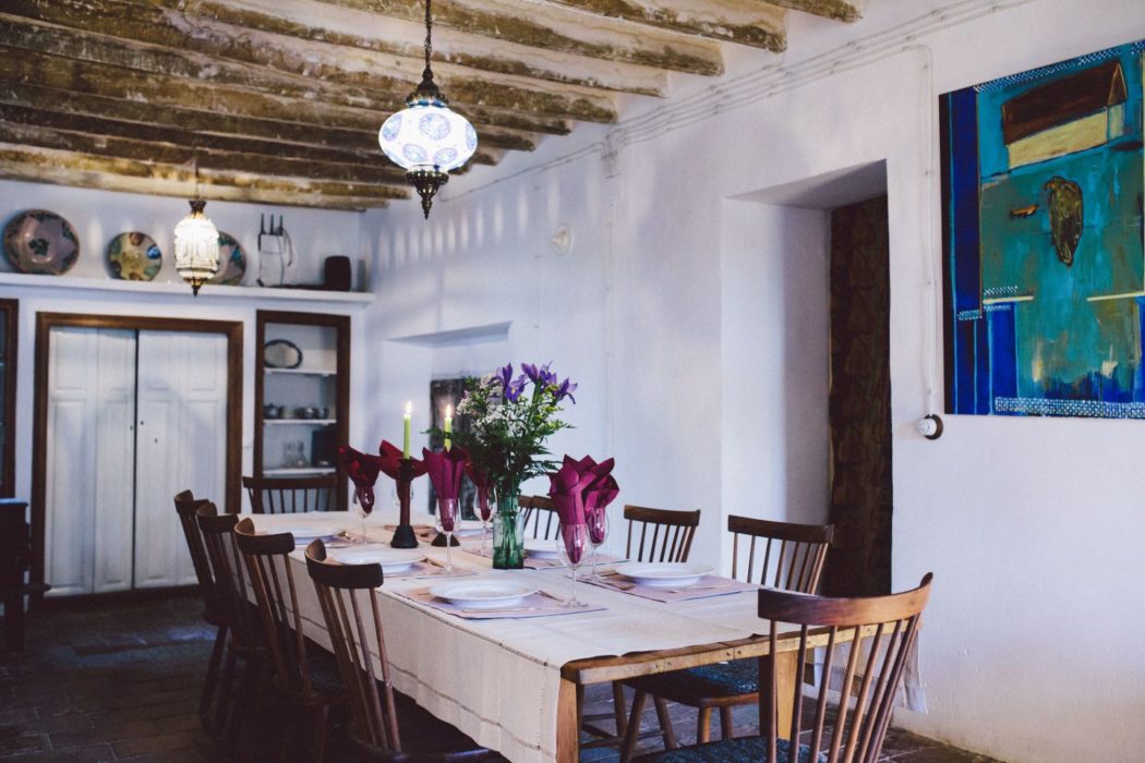 Dining room in a traditional Spain villa with white walls, wooden beams and artistic decorations.