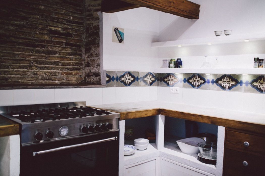 White walls kitchen with blue tiles, modern oven and white surfaces.