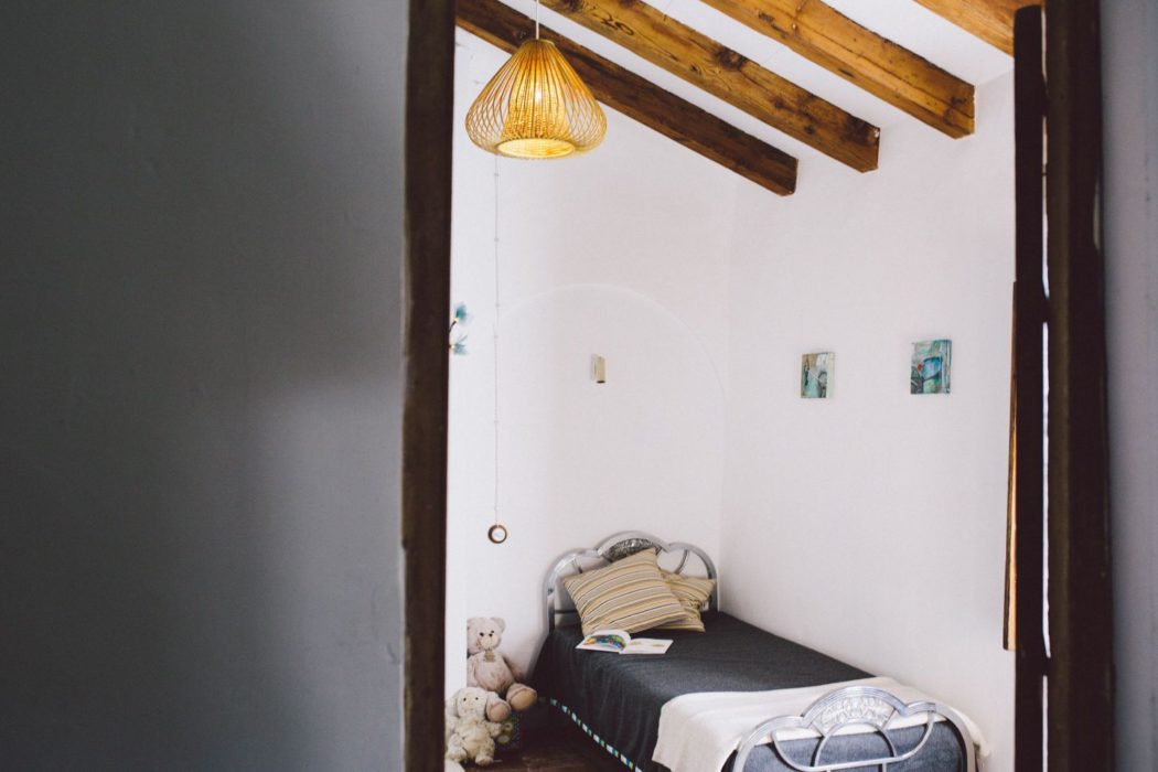 A small childrens' bedroom with single bed, open book and teddy bears.