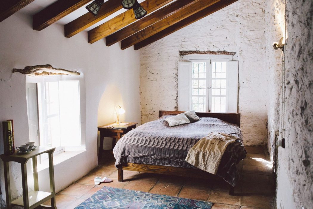 A traditional Spanish villa bedroom with large double bed, French windows and wooden ceiling beams