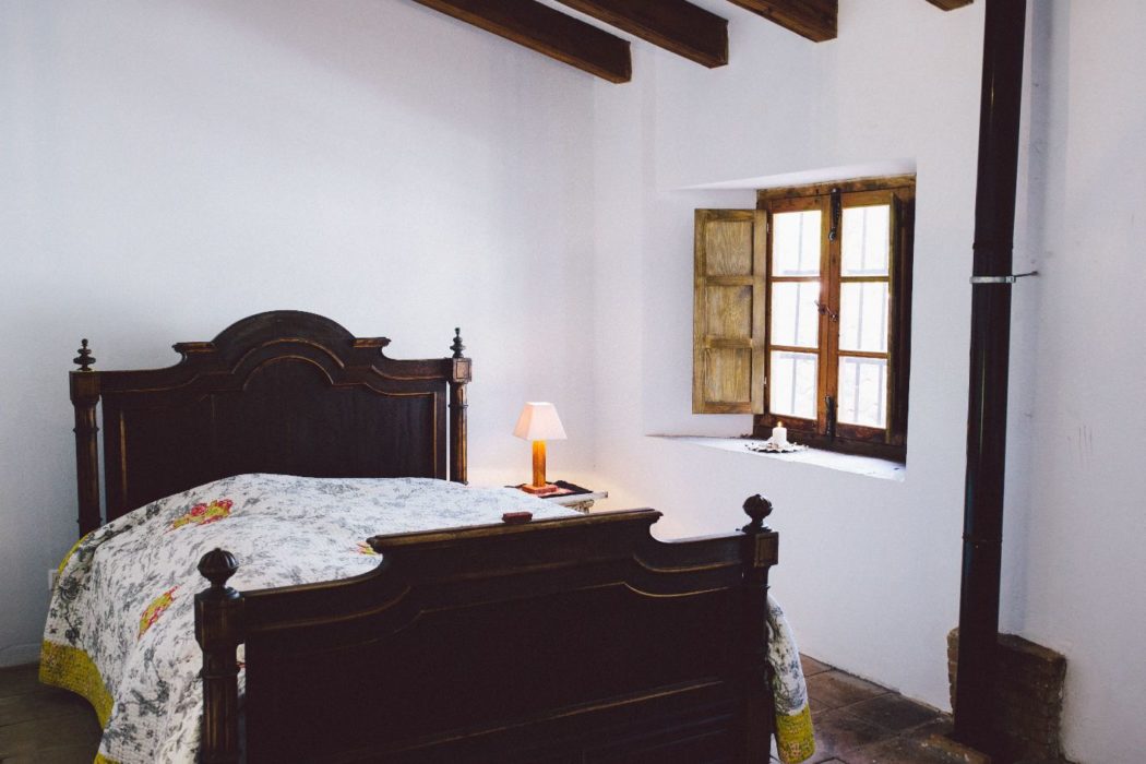 A Spanish villa bedroom with white walls and a large double bed with decorative quilts